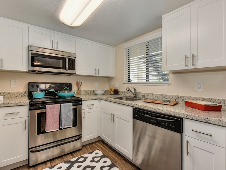 Kitchen with Granite Counters, Dishwasher, Oven, Microwave, Black/White Rug and White Cabinents